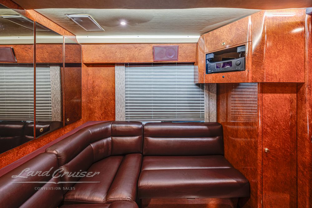 Full rear lounge seating in Prevost entertainer coach with rich cherry wood trim and leather upholstery