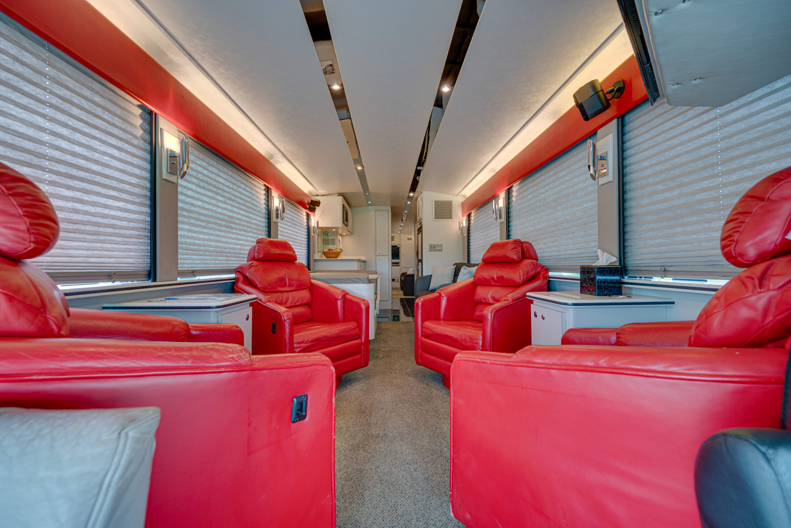 Inside view of an MCI Executive Day Coach for Sale featuring plush red oversized chairs.