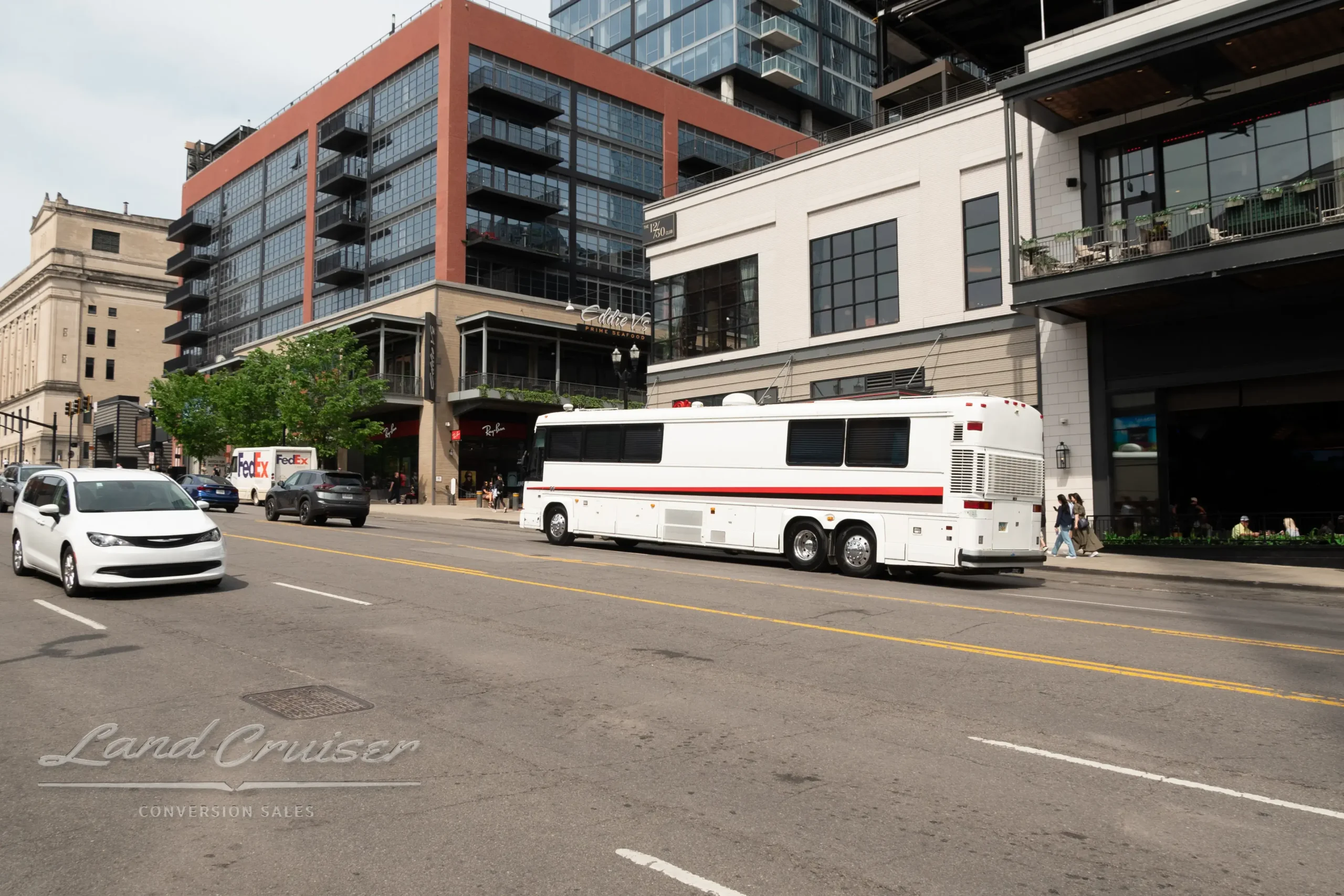 Triple axle MCI Executive Coach driving through intersection near downtown Nashville shops