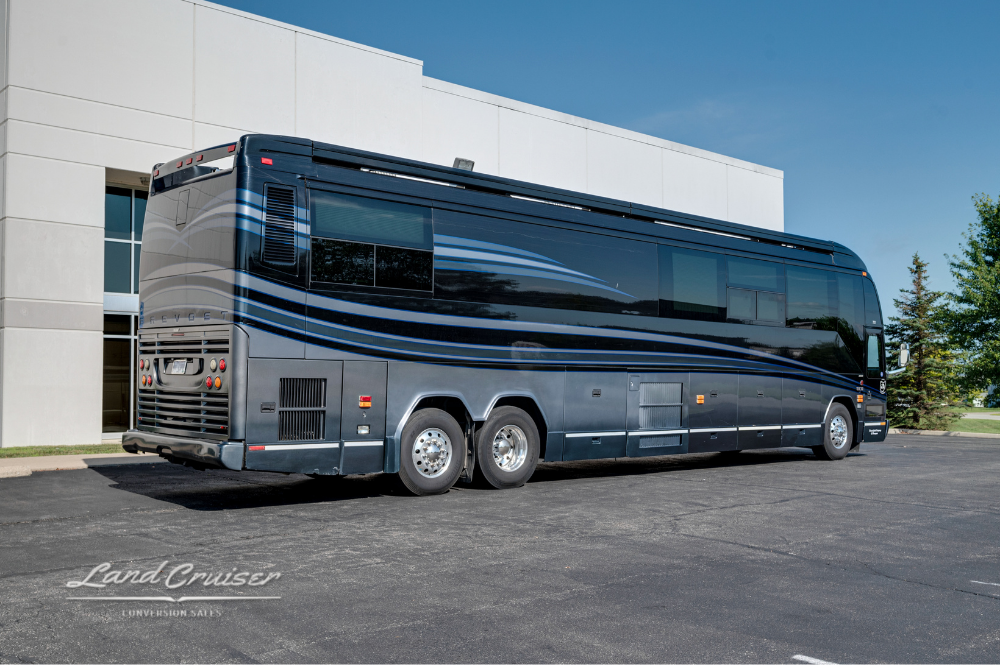 Rear corner view of the luxury executive bus, showing aluminum wheels, awning housing, and tail lighting.