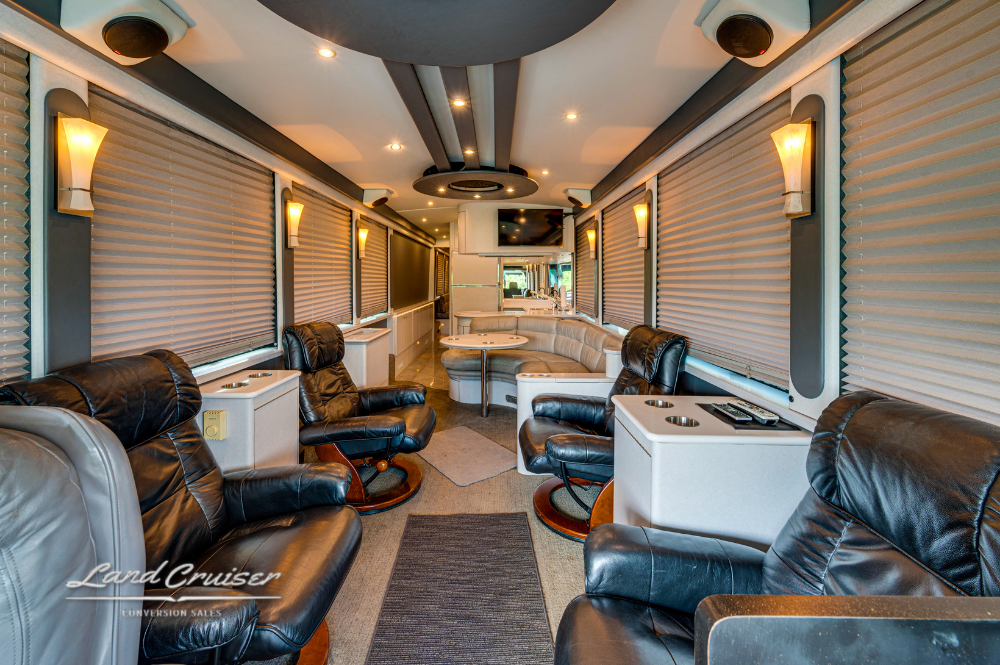 Executive lounge interior with black leather recliners and ambient ceiling lighting in Prevost motorcoach