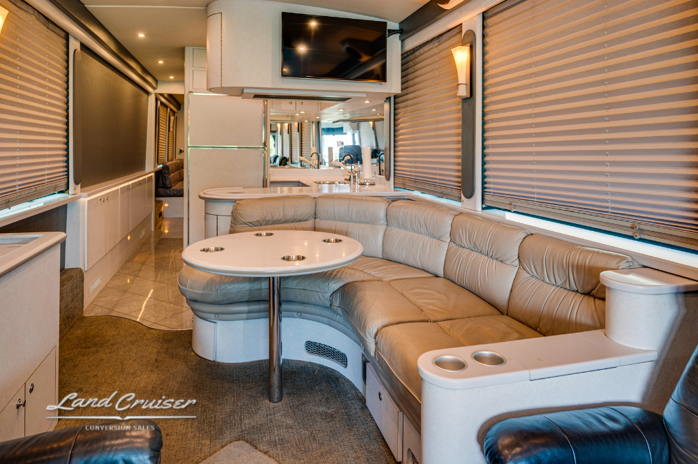 Curved leather lounge with integrated dinette table and cupholders in entertainer bus layout