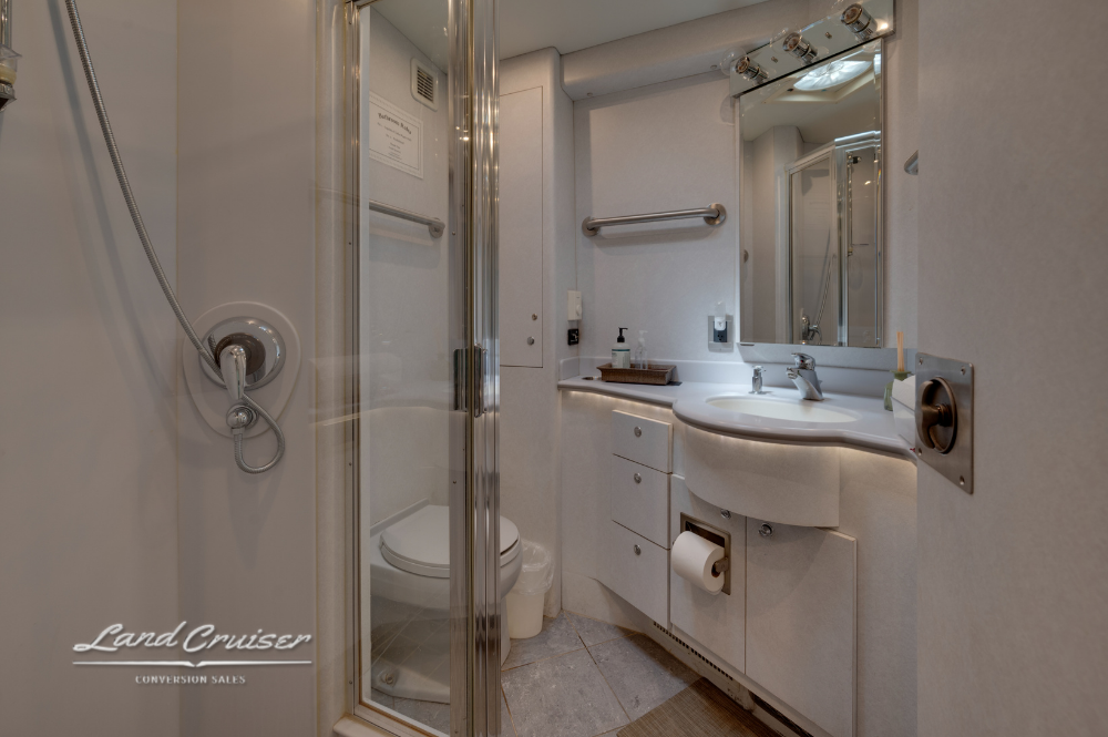 Luxury bathroom with residential toilet, vanity, and walk-in shower inside entertainer coach